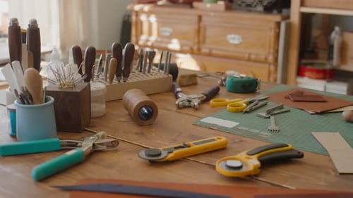 Workbench Cluttered with Various Crafting Tools and Materials for Leather Work