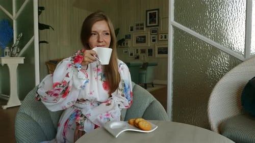 Woman Drinking Tea with Cookies in Sunny Room