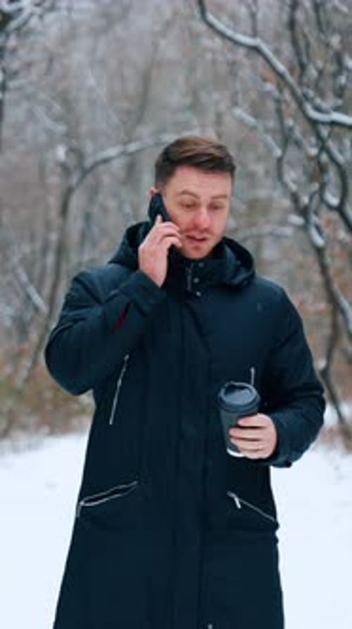 Man Talking on Phone with Coffee in Winter Forest