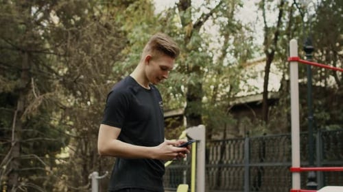 Portrait of a Caucasian Guy in Sportswear Who Takes a Break During a Workout on a Sports Field in