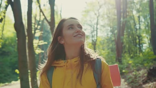 Pretty Smiling Caucasian Woman with Hiking Equipment Walks in Woods Looks Around Enjoys the Beauty