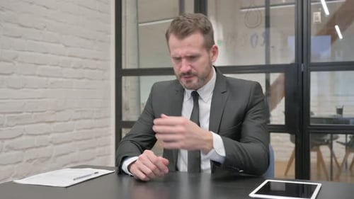 Man in Suit Frustrated at Desk in Office