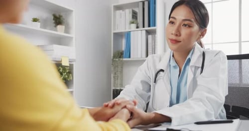 Caring Doctor Holding Patient's Hands in Office