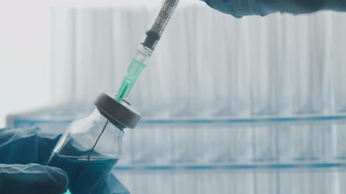 Syringe Draws Blue Liquid from Vial in Lab