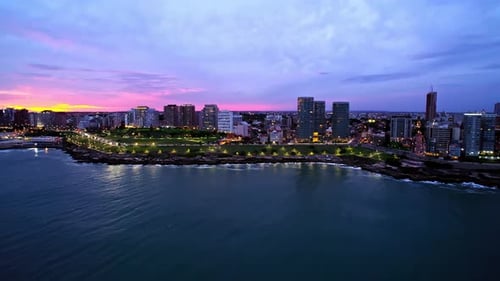 Órbita aérea de una vibrante puesta de sol sobre Mar del Plata y el Parque San Martín, Argentina