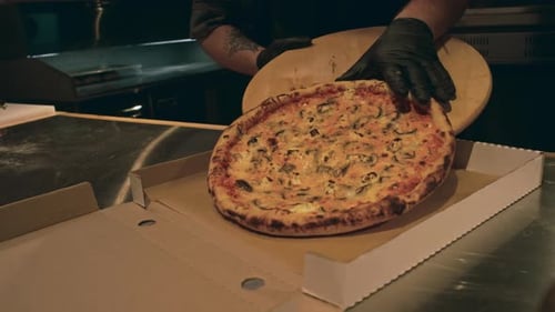 Hands of Chef Packing Freshly Baked Pizza in Box for Delivery