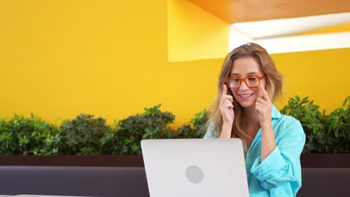 Happy Female Freelancer Using Laptop at Outdoor Cafe Table