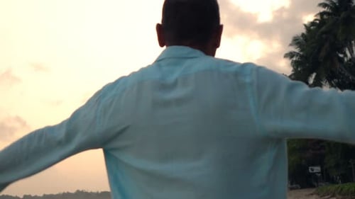 Man Walking on Beach During Sunset and Stretching Arms Super