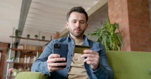 Man Uses Phone and Credit Card on Couch
