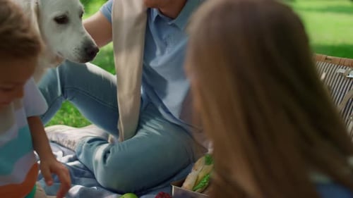 Loving family enjoying picnic with their golden retriever dog