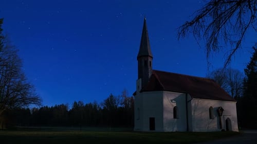Timelapse of moving stars over a chapel at night.