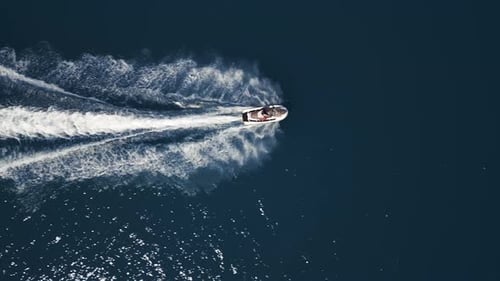 Aerial View of a Jet Ski Speeding Across Dark Blue Water Leaving a Dynamic White Trail Captured By