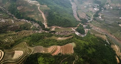 Flying over terraced hills in Vietnam towards a river and valley community. Sapa Vietnam.