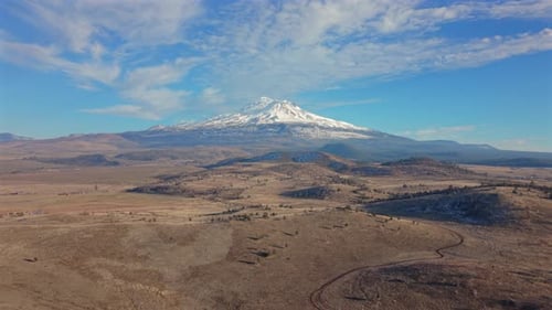 Montagne enneigée s'élevant au-dessus d'un vaste paysage aride sous un ciel bleu