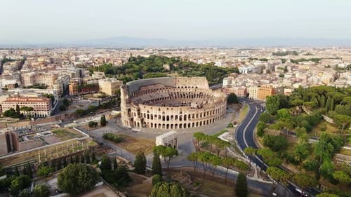 Drone flying backward over Colosseum in Rome - golden hour architectural view