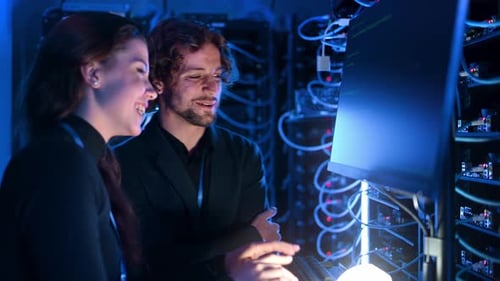 Two Technicians Collaborate in Server Room Environment