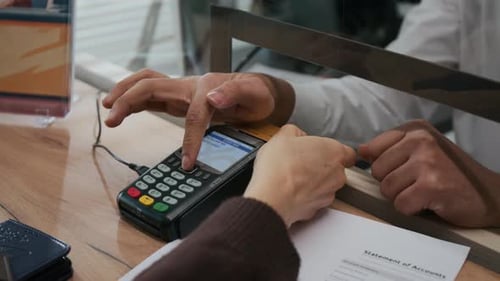 Close-up of Unrecognizable Hands Making Credit Card Payment in Bank
