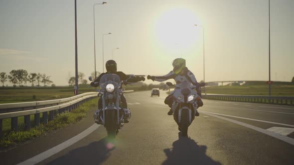Two motorcyclists riding different type of motorcycles fist bumping ...