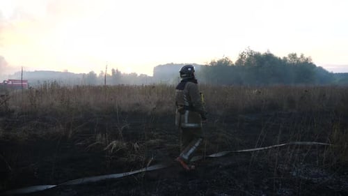 Firefighter Walking Through Burning Field at Sunrise