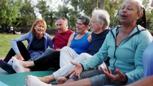 Multiracial, senior people having fun after yoga exercise class in nature at public park. Elderly