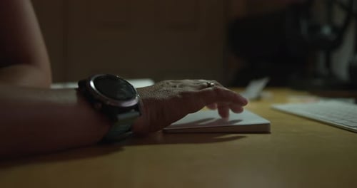 Frauenhand benutzt Maus und tippt auf der Tastatur bei schlechten Lichtverhältnissen
