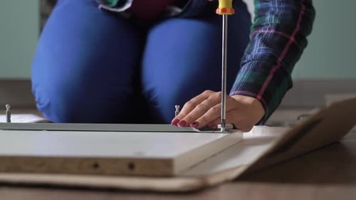 Woman Assembling Furniture at Home with Screwdriver