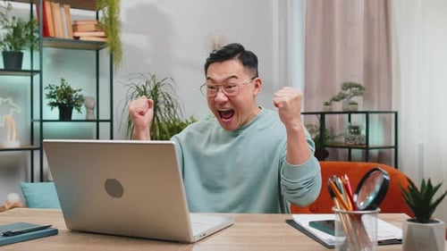 Excited Man Celebrates Laptop Success at Home
