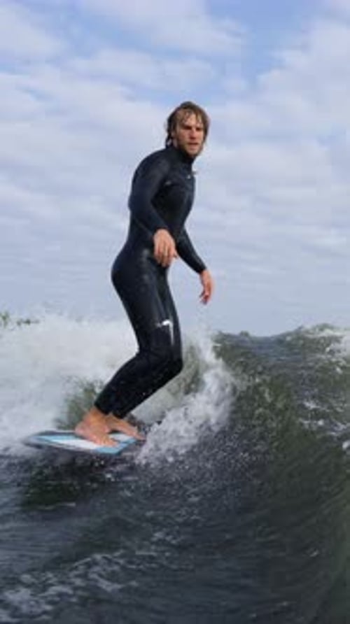 Man in Wetsuit Rides Wakeboard on Ocean Wave