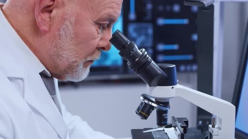 Senior Scientist Examines Sample Through Microscope in Lab