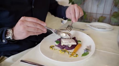 VIP-Kunden in einem schicken Restaurant essen Fisch mit Beilage und Gemüse mit einer Gabel