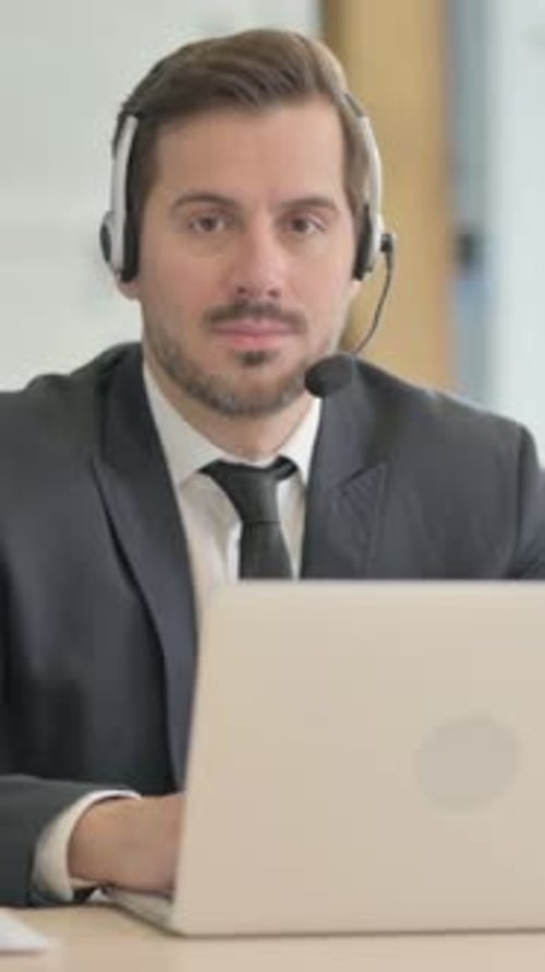 Businessman with Headset Looking toward Camera in Call Center, vertical video