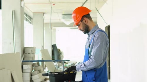 Construction Worker Selecting Screwdriver From Toolbox On Site