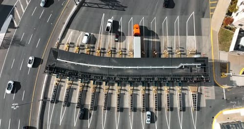 Top down aerial of traffic passing through toll plaza booth to pay money electronically.