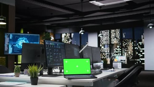 Modern Office Interior with Green Screen Laptop at Night