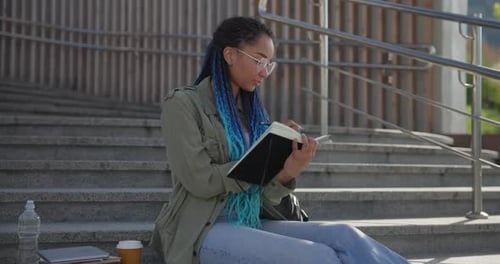 Stylish Woman Studying Outdoors on Urban Campus Steps