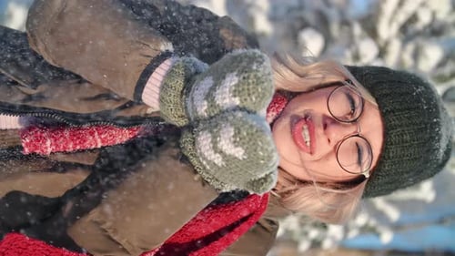 VERTICAL VIDEO POV Portrait Happy Winter Woman Blowing Snowflakes Sunny Frozen Forest Closeup Slowmo