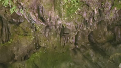 Kleine Wassertropfen, die von den Felsen in den Fluss tropfen, Nahaufnahme KREATIVER Nachschub des