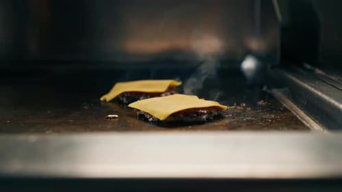 kitchen in a restaurant, close-up, the chef puts slices of cheese on the grilled smash burger cutlet