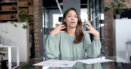Biracial casual businesswoman having video call talking and gesturing in office, slow motion