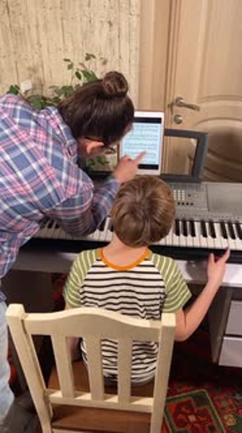 Adult Helping Child with Piano Lesson at Home