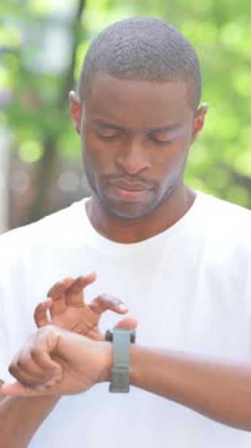 Young African Man Using Smartwatch Outdoor in Park, Vertical Video