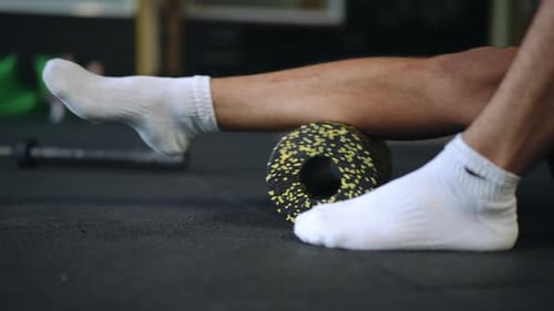 Adult Man Rolling Calf Muscle with Foam Roller