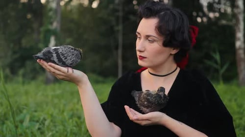Uma mulher elegante segura graciosamente pássaros em um ambiente natural sereno e pacífico do