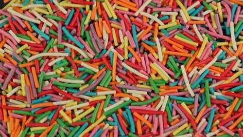 Colored confectionery sprinkles rotate in macro. Culinary topping for desserts and baked goods