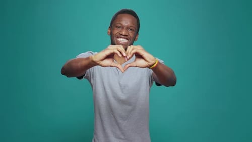 Man Makes Heart Shape With Hands Smiling