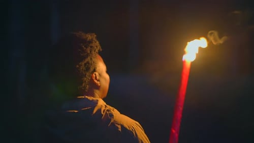Young Adult Holding Lit Torch in the Dark
