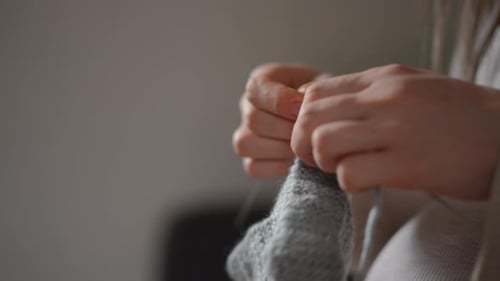 Woman Knitting with Grey Yarn in a Home Setting