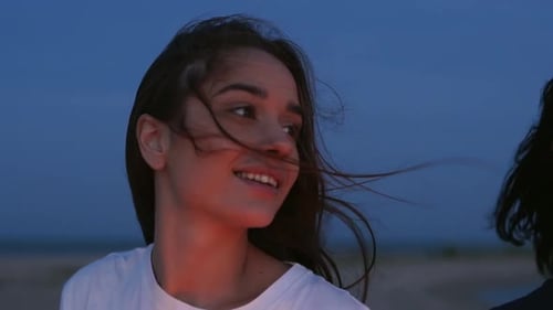 Amigas paseando, bailando, divirtiéndose por la noche, fiesta en la playa con bengalas en la mano, jóvenes