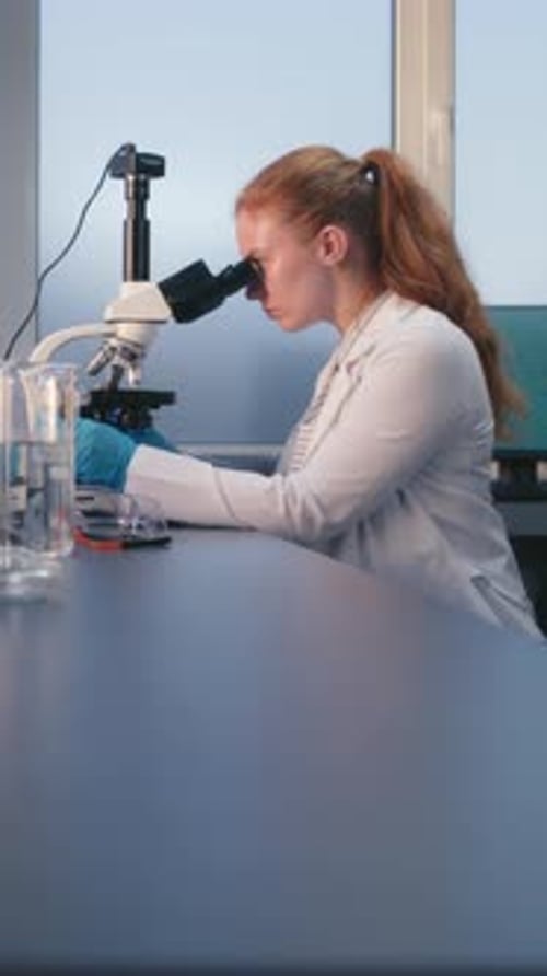 Woman Scientist Working in a Laboratory with Microscope