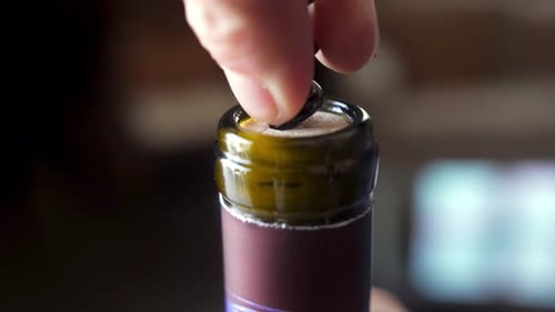 close-up shot of a corkscrew being inserted into a wine bottle's cork, capturing the moment of openi
